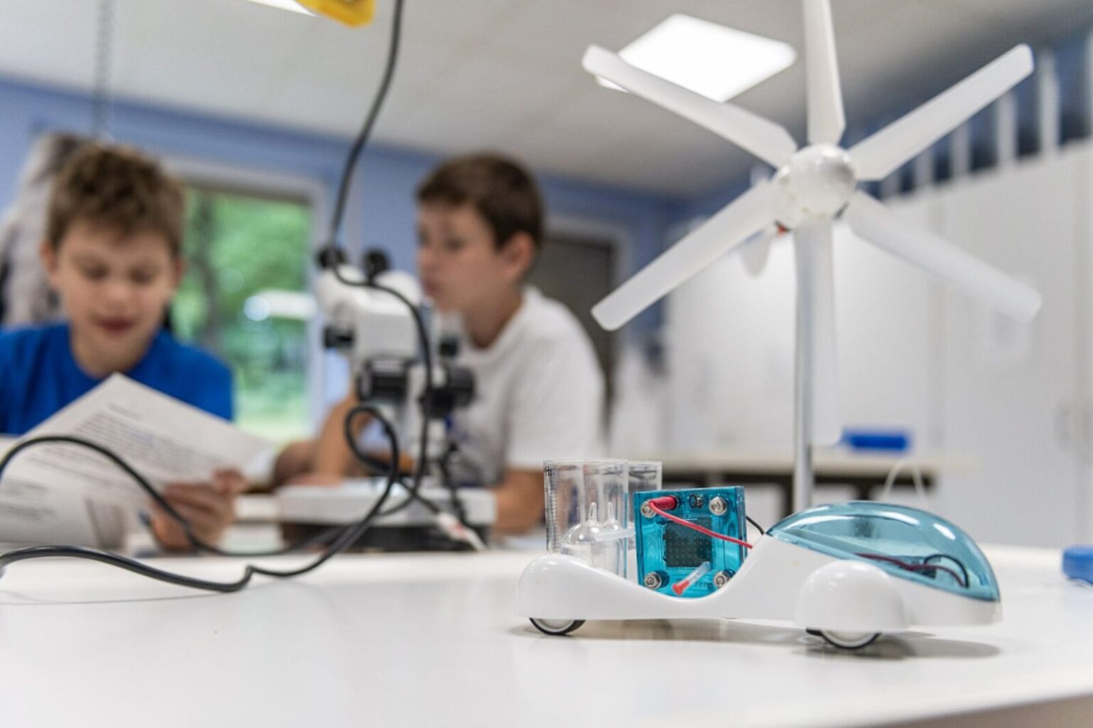 Kinder beim Bau eines fahrenden Spielzeugwagens mit Wasser, Strom und Windrad