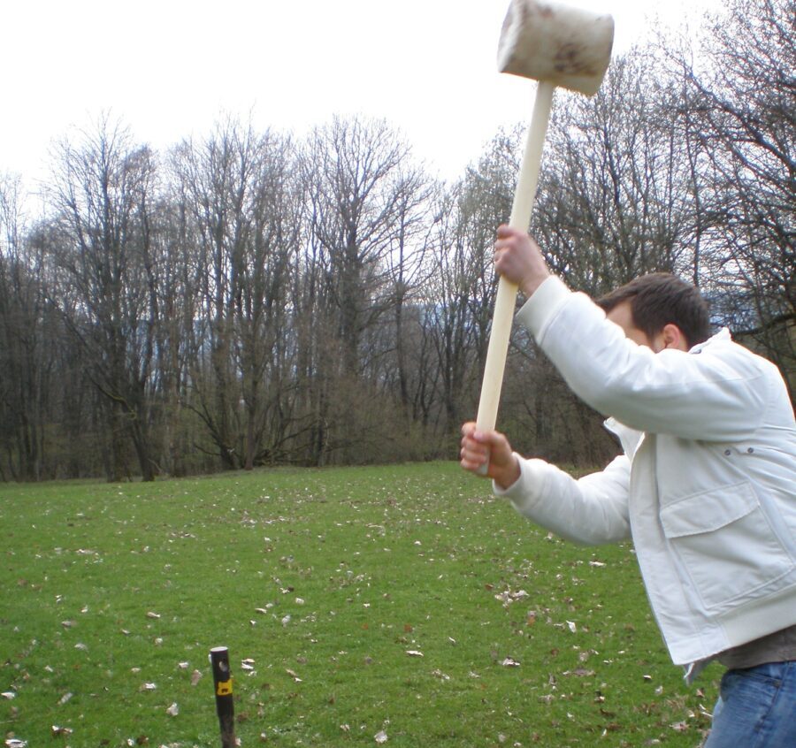 Ein Mann haut mit einem Pürckhammer auf einen Bohrstock.