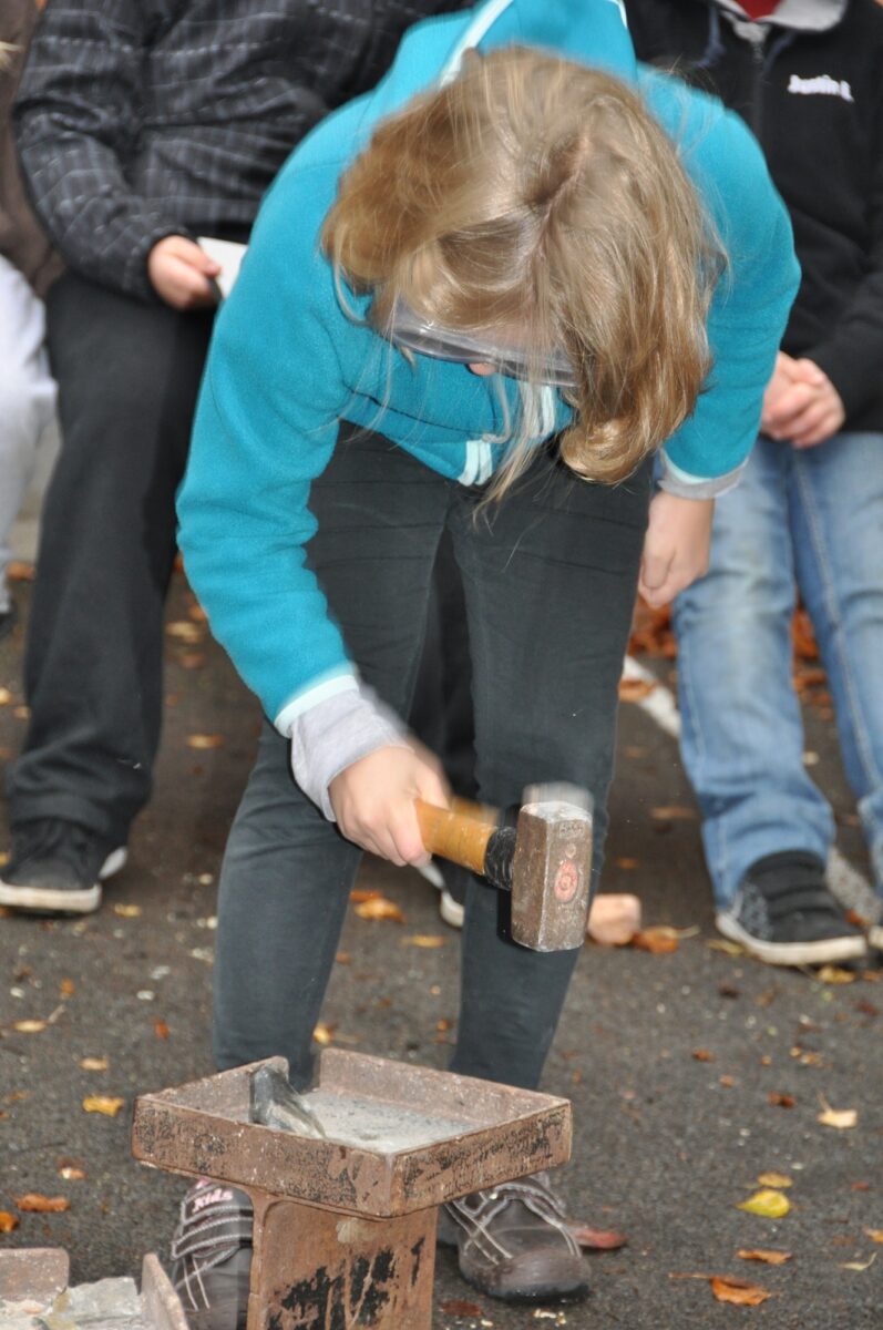 Ein Mädchen zertrümmert mit einem Hammer einen Stein