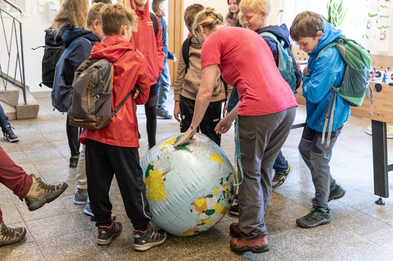 Die Studienhausleiterin zeigt auf einen Wasserball-Globus die Längen- und Breitengrade