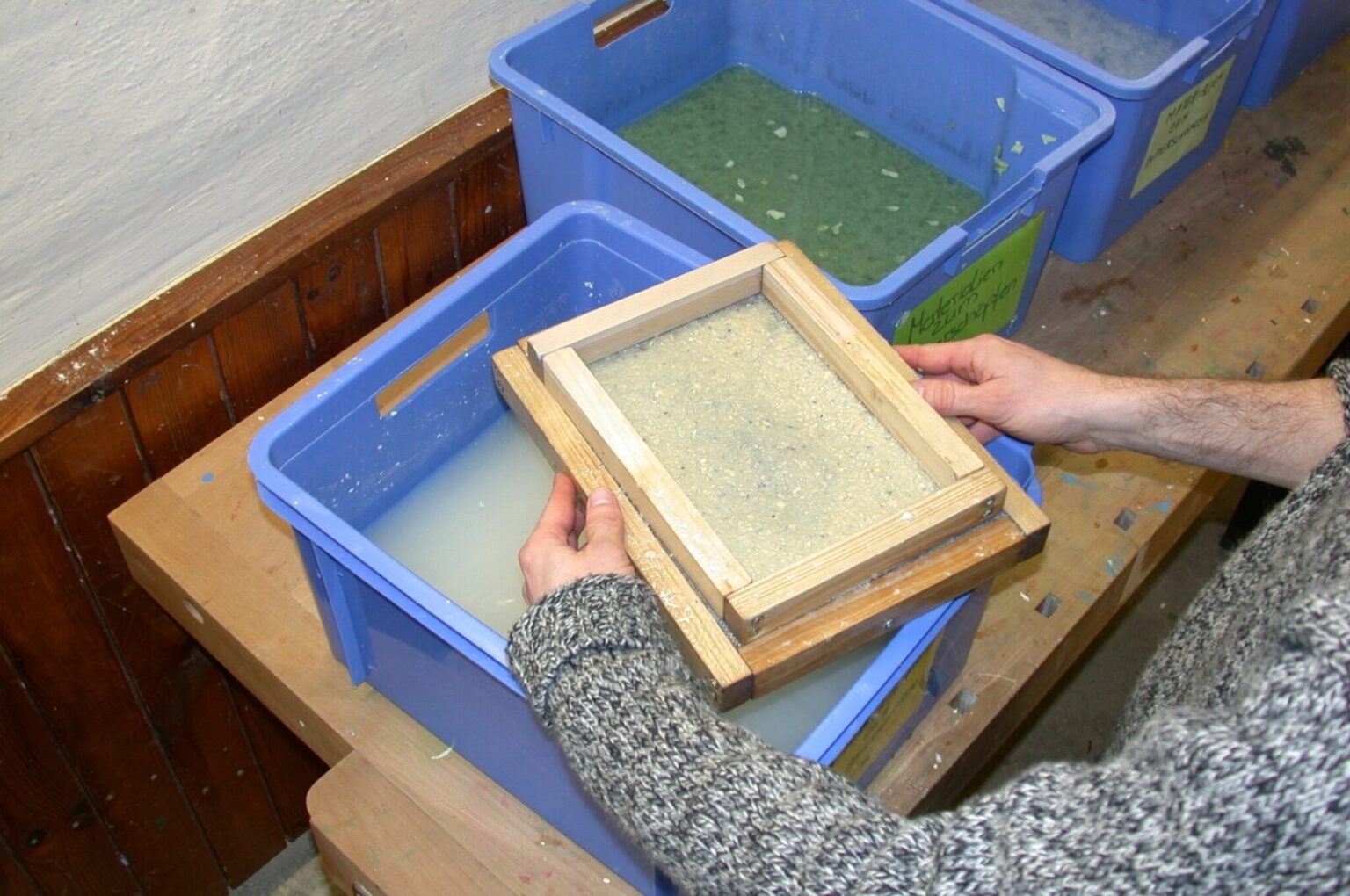 Der Schöpfrahmen liegt zum Abtropfen auf dem Rand der Wanne